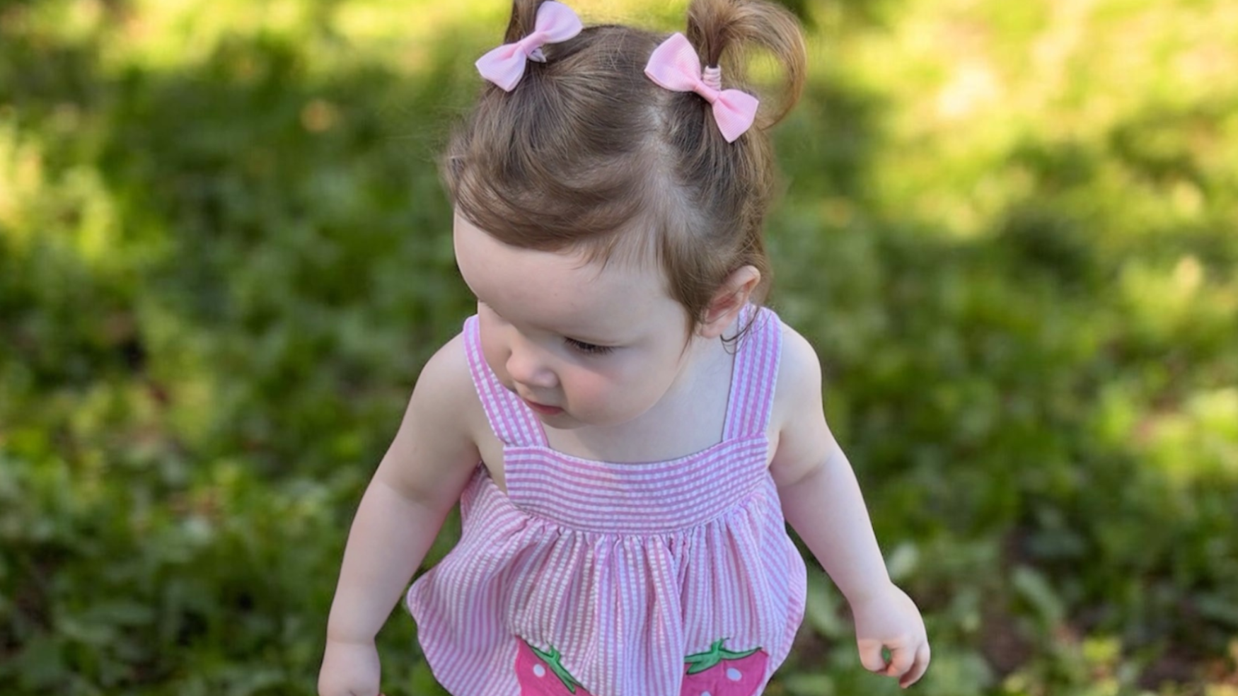 toddler girl in pink seersucker bubble romper with strawberry detail